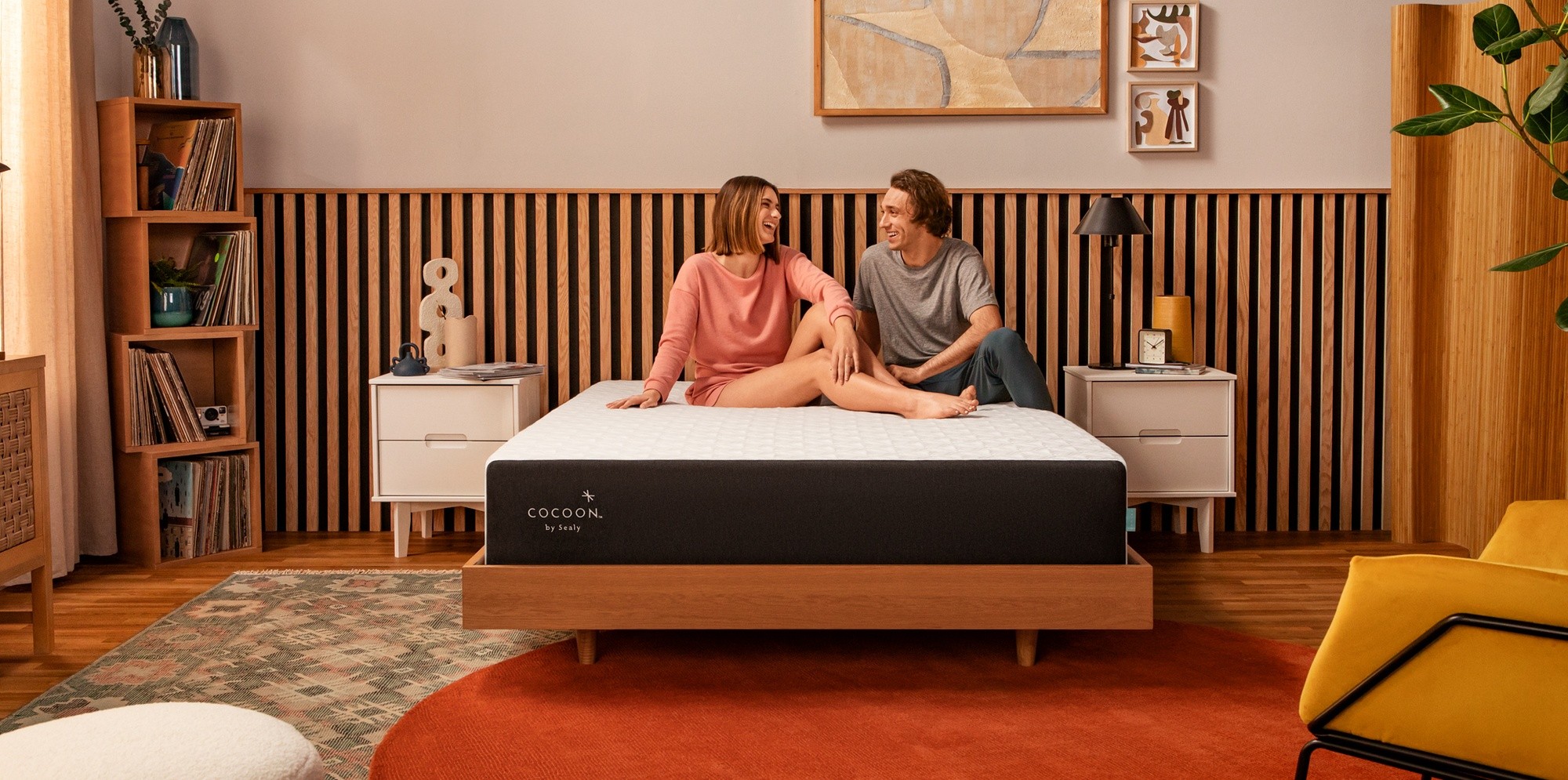 a couple sitting on a cocoon chill hybrid mattress laughing