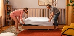 a couple putting on sheets on a cocoon chill hybrid mattress