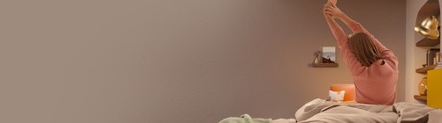 Woman sitting on Cocoon mattress with arms raised - offer page hero